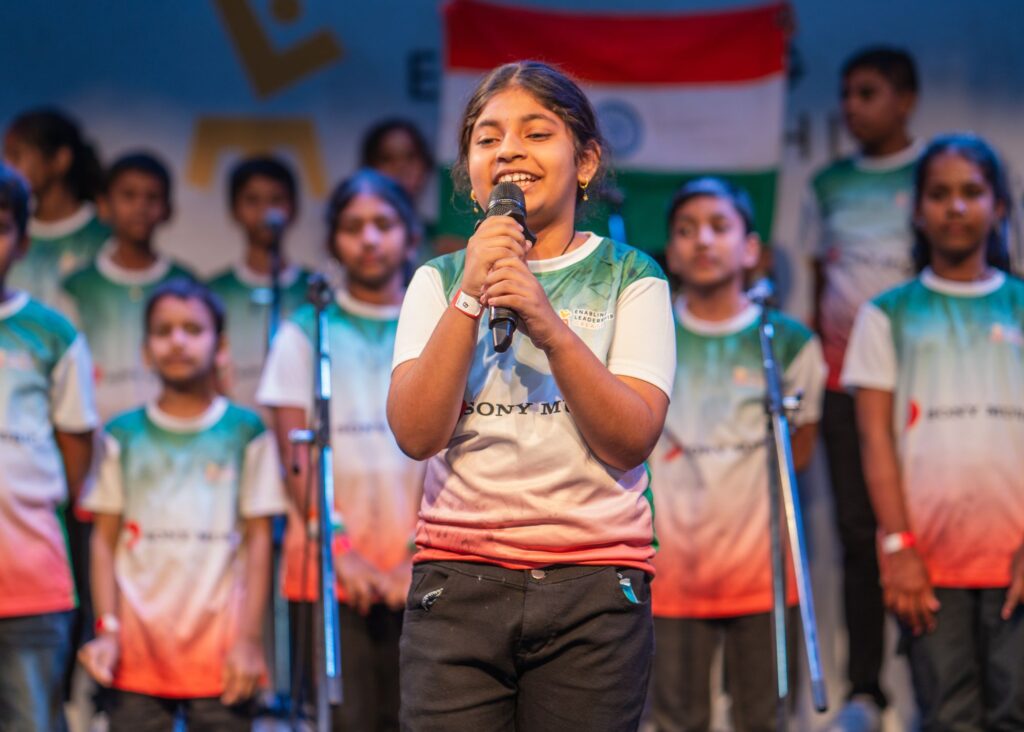 A girl from belonging to the Hyderabad Enabling Leadership Creat programs takes stage to introduce their team's song